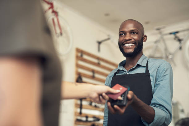 plan d’un beau jeune homme debout dans son magasin de vélos et aidant un client avec son achat - vending machine photos et images de collection