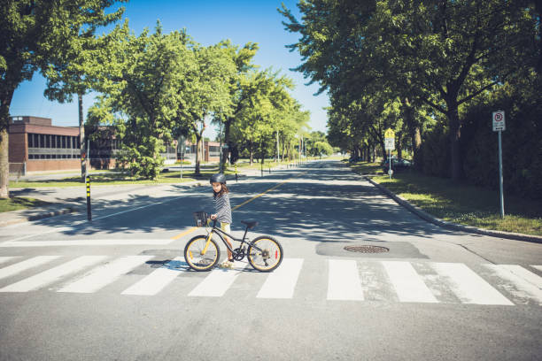 One little girl crossing the road with her bike One little girl crossing the road with her bike crossing sign stock pictures, royalty-free photos & images