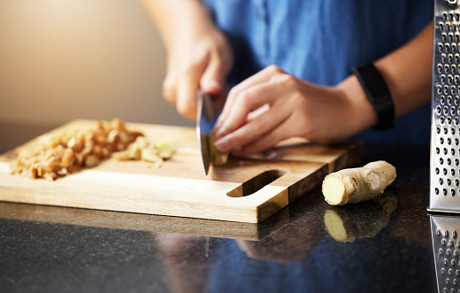 Hands of young female chopping fresh onion on wooden board