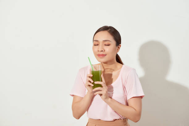istock Young woman drinking green juice with straw 1330038726