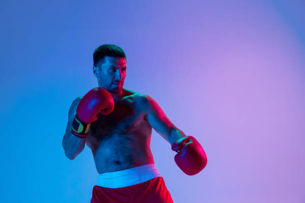 istock One man, professional boxer in sportwear boxing on studio background in gradient neon light. Concept of sport, activity, movement, wellbeing. 1330038923
