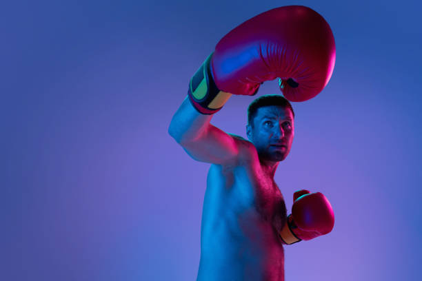 istock Close-up professional boxer in sportwear boxing on studio background in gradient neon light. Concept of sport, activity, movement, wellbeing. 1330038933