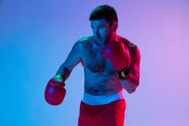 istock One man, professional boxer in sportwear boxing on studio background in gradient neon light. Concept of sport, activity, movement, wellbeing. 1330038935