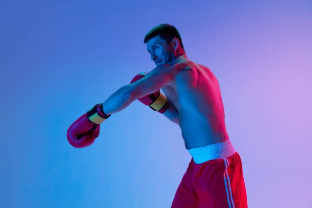 istock One man, professional boxer in sportwear boxing on studio background in gradient neon light. Concept of sport, activity, movement, wellbeing. 1330038938