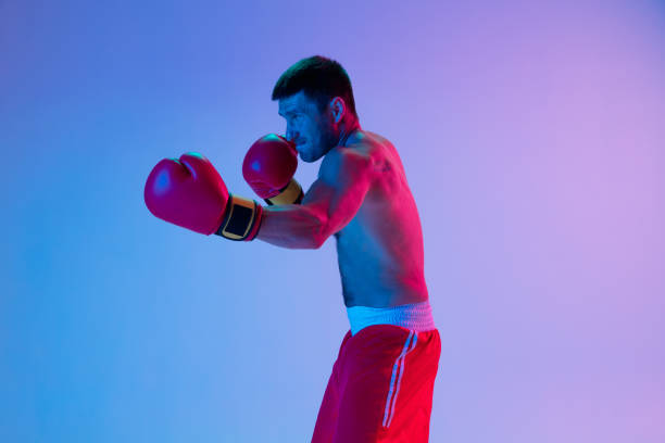 istock One man, professional boxer in sportwear boxing on studio background in gradient neon light. Concept of sport, activity, movement, wellbeing. 1330038966