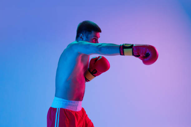 istock One man, professional boxer in sportwear boxing on studio background in gradient neon light. Concept of sport, activity, movement, wellbeing. 1330038970