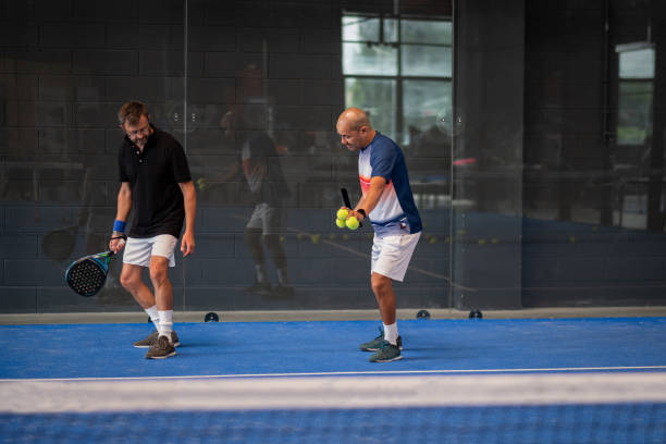 monitor unterrichten padel-klasse für mann, seinen schüler - trainer lehrt junge, wie man padel auf indoor-tennisplatz spielt - racketball racket ball court stock-fotos und bilder