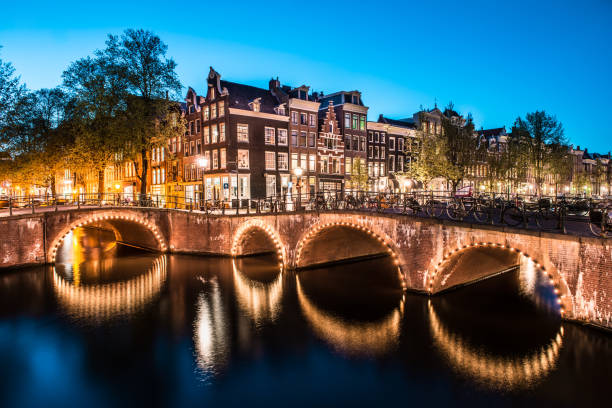 belle vue sur les ponts du canal d’amsterdam et les lumières la nuit, pays-bas - magere brug photos et images de collection