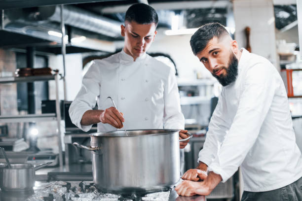 istock With help from other employee. Chef in white uniform cooking food at kitchen. Busy day at work 1330043154