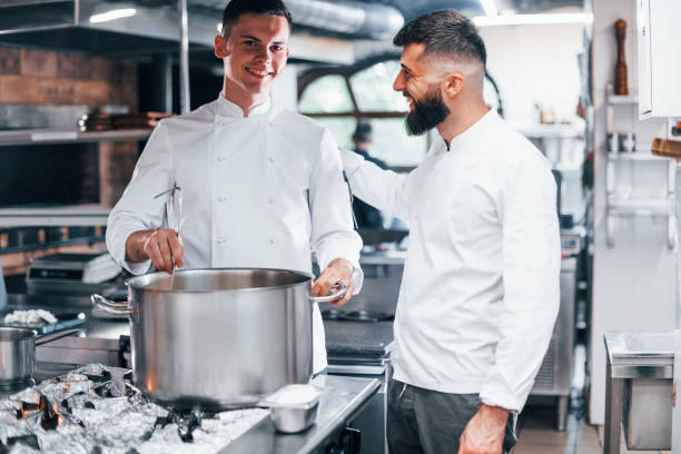 istock With help from other employee. Chef in white uniform cooking food at kitchen. Busy day at work 1330043230
