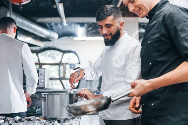 istock People in white uniform cooking food at kitchen together. Busy day at work 1330043326