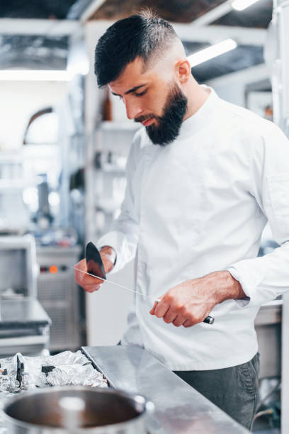 istock Chef in white uniform standing at kitchen. Holding knives in hands 1330043442