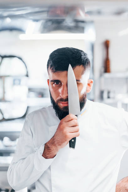 istock Chef in white uniform standing at kitchen. Holding knife in hands 1330043950