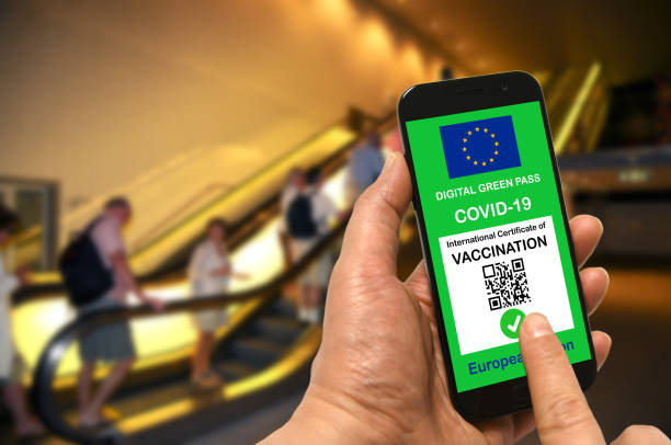 A man in a shopping mall holds a smartphone with the European Union digital green pass for Covid-19 in his hand. Safety concept for Coronavirus and the Green pass stock photo