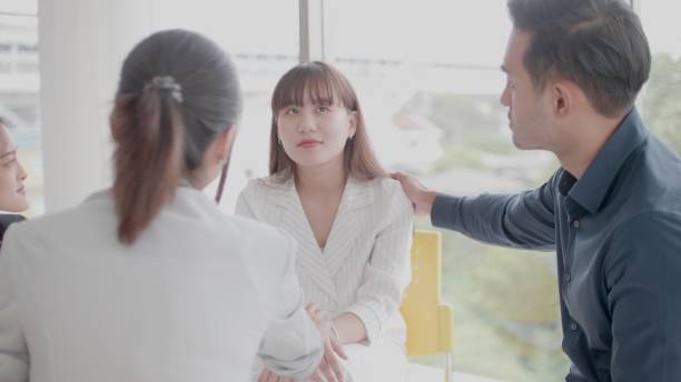 istock Psychological therapy group. Various age of asian people talking, sharing personal problems, show compassionate supporting desperate unhappy woman. Depressed female patient suffering from bullying. 1330049621