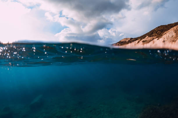 istock Split shot with coastline and underwater scene with sun rays and transparent ocean water. 1330051555