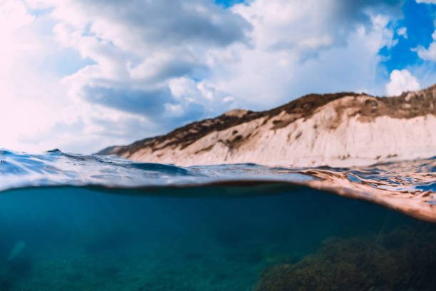 istock Split shot with coastline and underwater scene with sun rays and transparent ocean water. 1330051594