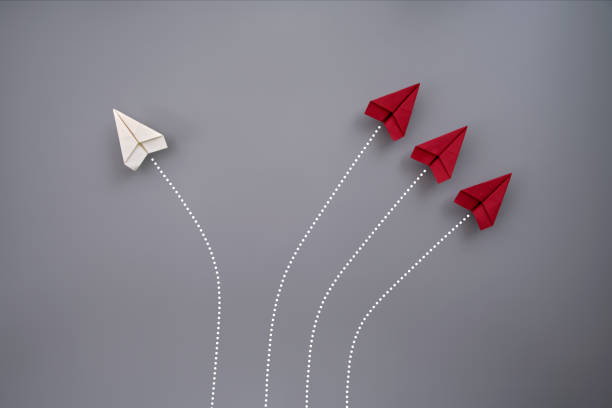 Trying something new One white and three red folded paper planes flying against gray background paper airplane photos stock pictures, royalty-free photos & images
