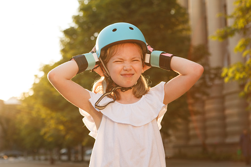 Young rollerblader girl looking annoyed, trying to take off her helmet