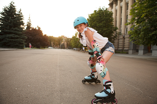 Excited young girl enjoying rollerblading in the city, wearing protective gear, copy space