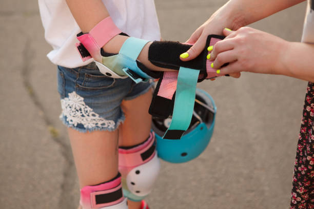 Rollerblader girl enjoying skating outdoors Cropped close up of a woman putting wrist guard rollerblading protective gear on a young girl elbow pad stock pictures, royalty-free photos & images