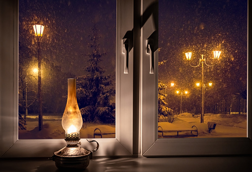 retro kerosene lamp on the windowsill on a winter night