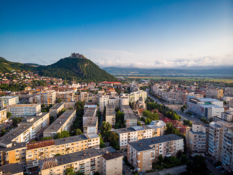 Aerial image captured by drone depicting the ancient city of Deva, in the Transylvania region of Romania. We can see the city's sprawling houses and apartment blocks, as well as the ancient citadel which crowns this Romanian town.