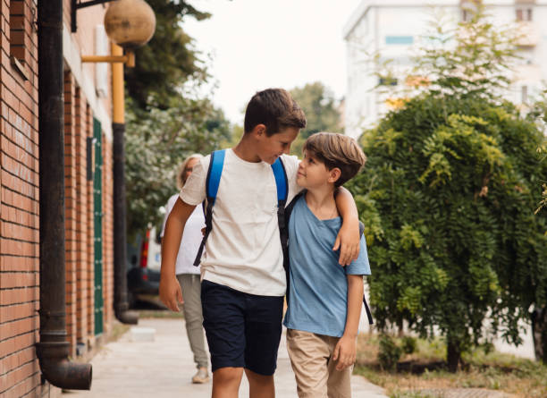 Schoolboys going to class, hugging and smiling. stock photo