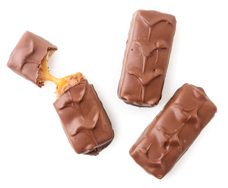 Chocolate bar with nougat and caramel, whole and broken close-up on a white background, isolated. Top view