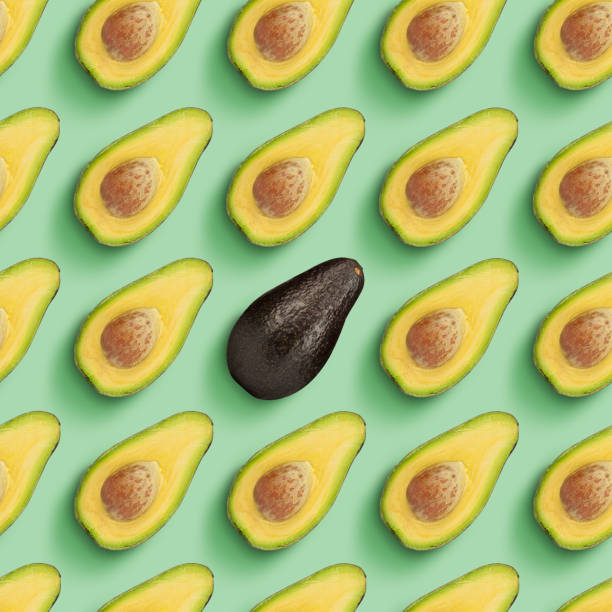 istock Halves and one whole ripe avocado arranged over light green background. Modern artwork, collage. 1330061085