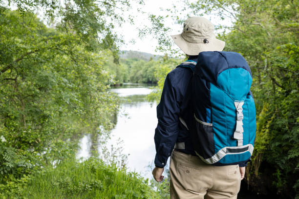 istock Rear view of a Male Backpacker looking at a river 1330062214