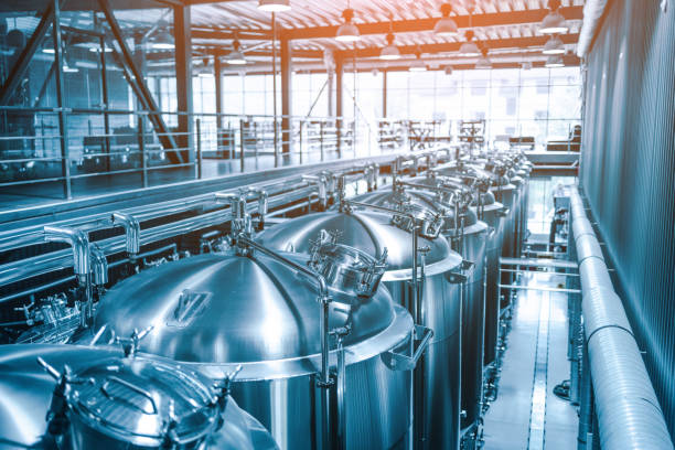 Private microbrewery. Modern beer plant with brewering kettles, tubes and tanks made of stainless steel Private microbrewery. Modern beer plant with brewering kettles, tubes and tanks made of stainless steel. Toning, shallow depth of field, sunlight mini wheat cereal stock pictures, royalty-free photos & images