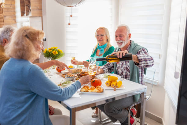 istock Senior friends pouring wine while having Thanksgiving dinner 1330066774