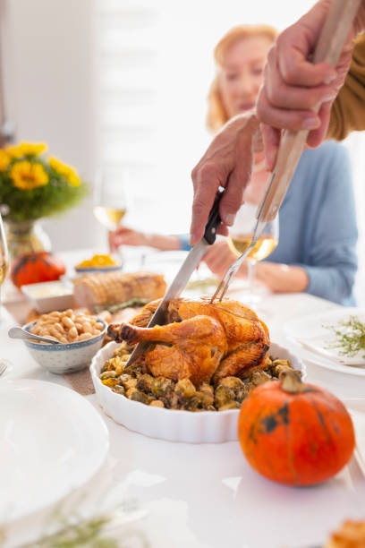 istock Close up of man cutting chicken over Thanksgiving dinner 1330066837