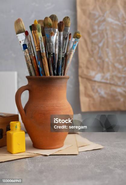Paint brush in clay jug and palette on wooden table background. Oil painting  and art still life Stock Photo by seregam