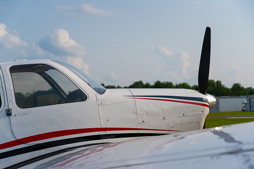 Light aircraft on a spacious airport apron. White wings against a blue sky. Empty airfield as a flight school concept.