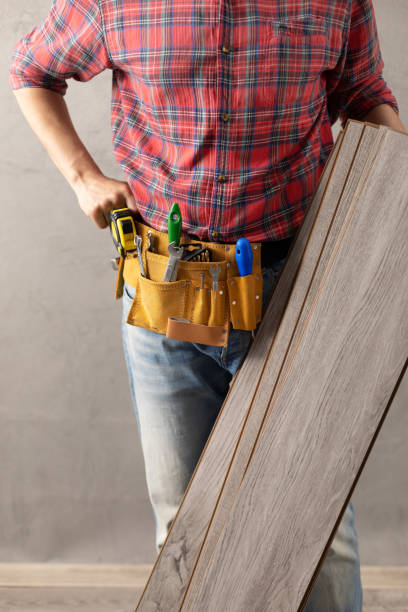 hombre trabajador que sostiene el tablón de piso laminado y la correa de herramientas. mano masculina y herramientas de construcción. concepto de renovación - wood laminate flooring floor nail hammer fotografías e imágenes de stock