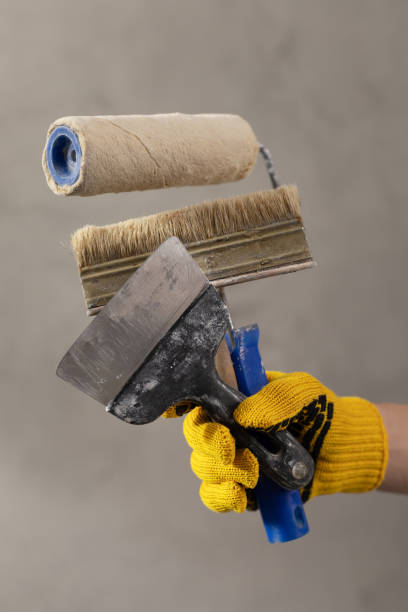 istock Construction worker man holding paint roller tool near concrete or plaster wall. Male hand and construction tools for house room renovation 1330068021