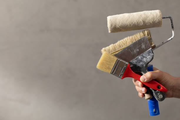 istock Construction worker man holding paint roller tool near concrete or plaster wall. Male hand and construction tools for house room renovation 1330068031