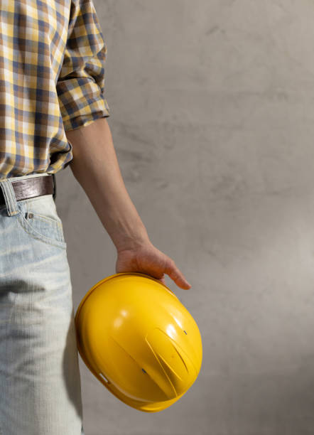 istock Man worker holding construction helmet and tool belt near wall. Male hand and construction tools 1330068032