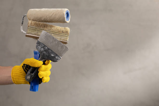 istock Construction worker man holding paint roller tool near concrete or plaster wall. Male hand and construction tools for house room renovation 1330068082