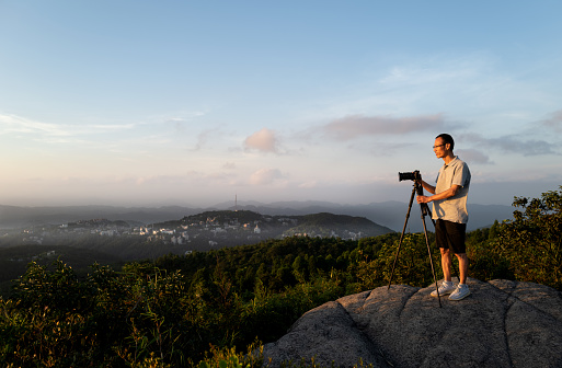 Asian male artist taking pictures at the top of the mountain