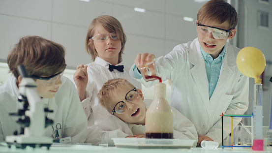 Elementary school students studying in laboratory. Working with gurgling liquid