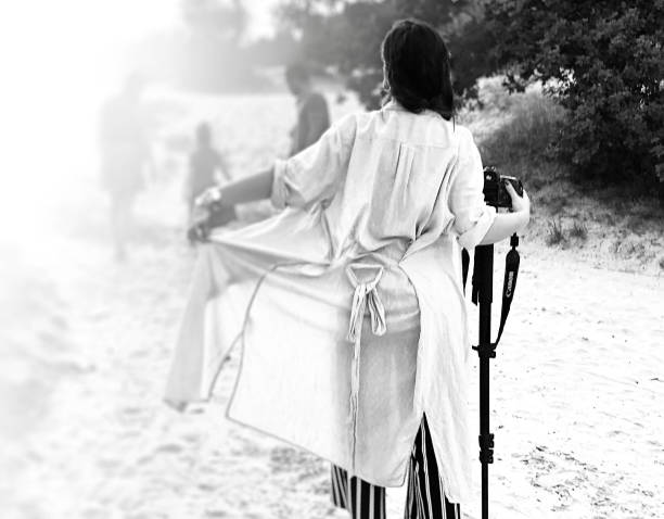 A woman collects flowers at the forest edge.