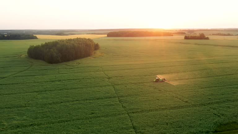 Aerial Tractor Trailer Sprays Mineral Fertilizer On Agricultural Field At Sunset