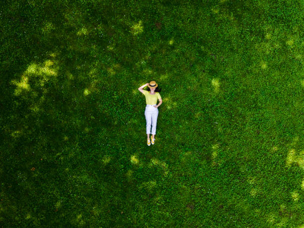 vue aérienne d’une femme allongée sur de l’herbe verte - être étendu photos et images de collection