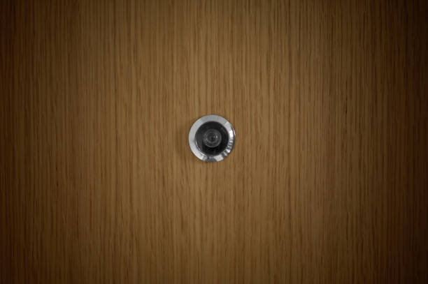 metal peephole in the center of an oak door detail of a metal peephole in the center of an oak door peep hole stock pictures, royalty-free photos & images