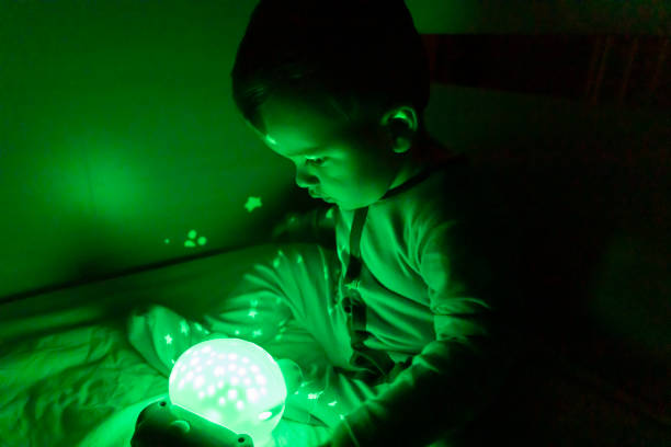 istock Little cute baby boy playing with a night light. Low lighting. 1330077605