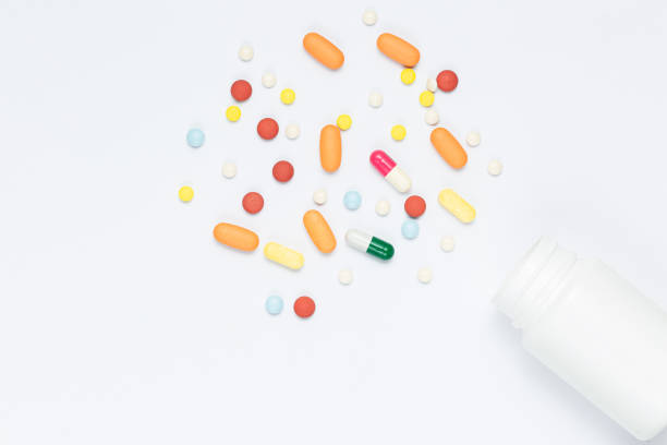 istock pills and pill bottles on white background,Flat lay composition with bunch of different colorful pills scattered on table from popped plastic bottle. Pile of opened medication on white paper textured background. Close up, copy space for text 1330079104