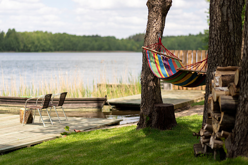 Holiday time view with colorful hammock hanging between trees by the lake